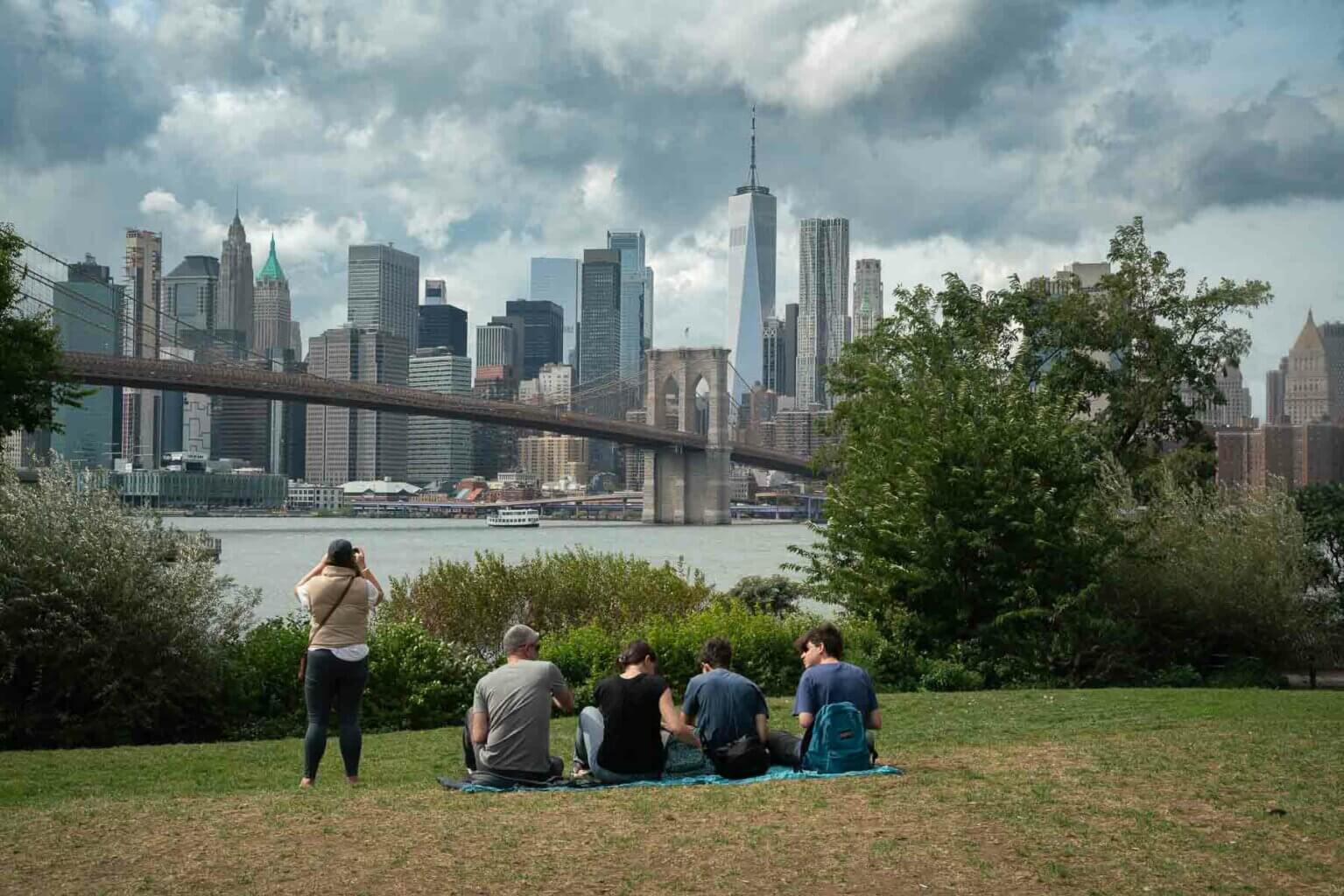 people picnicking at Brooklyn Bridge Park looking at the NYC skyline views in DUMBO