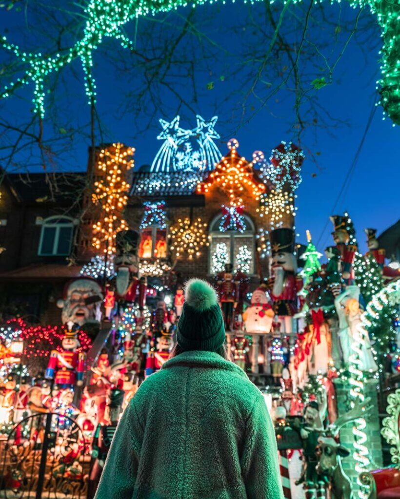 A vertical image of a girl looking at Lucy Spata House Dyker Heights Lights at Christmas in Brooklyn