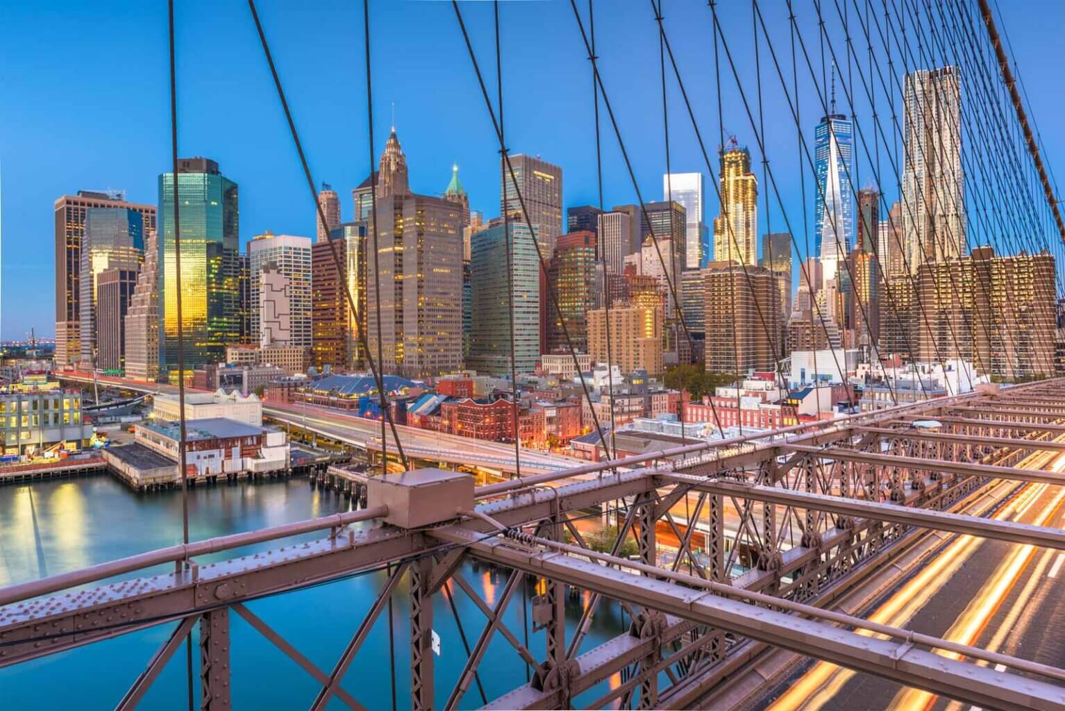 View of Brooklyn Bridge with Car Trails and Lower Manhattan Skyline at Sunset