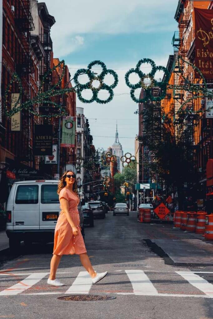 Megan walking through Little Italy with the Empire State Building in the backdrop in NYC