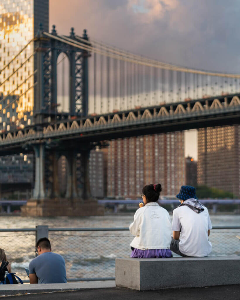 A couple eating Icecream in front of Jane's Carousel with the Manhattan Bridge in the background at Brooklyn Bridge Park in DUMBO