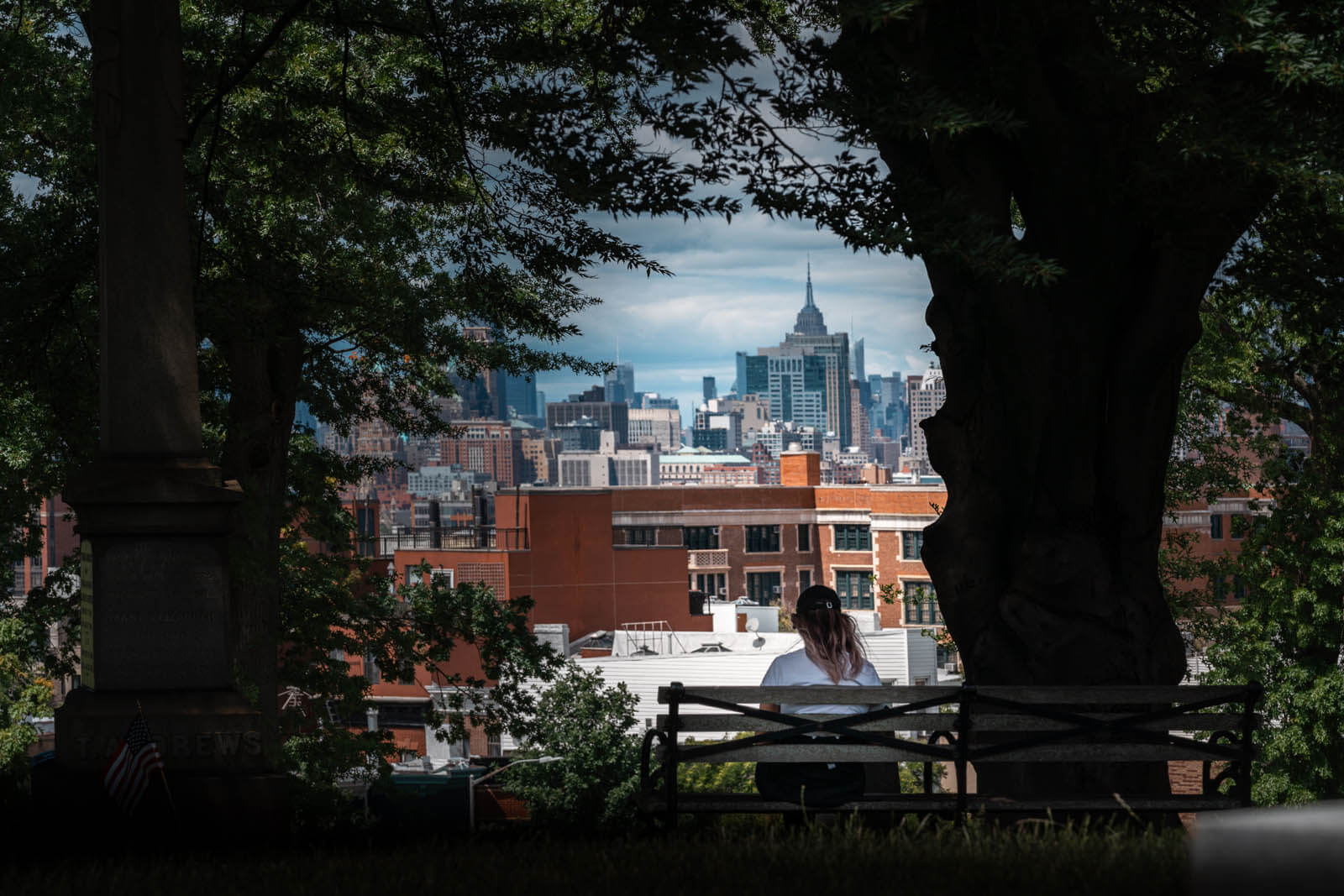 Megan sitting on Bench in Greenwood Cemetery with a view of the NYC skyline