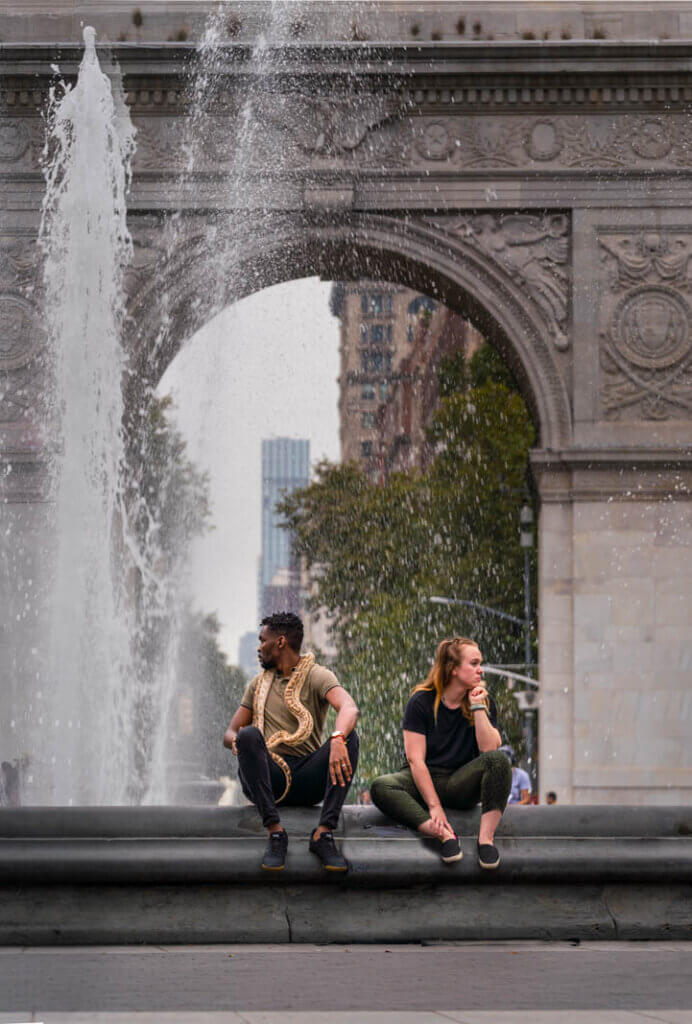 People watching at Washington Square Park in Manhattan a man with a snake at the fountain