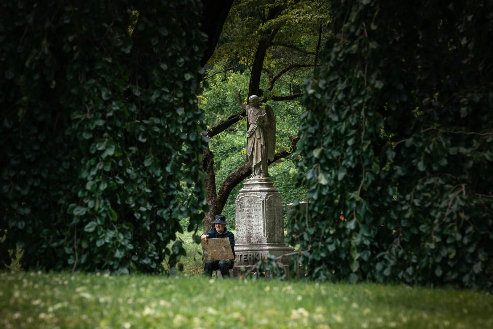 man painting next to an angel tombstone in Greenwood Cemetery in Brooklyn