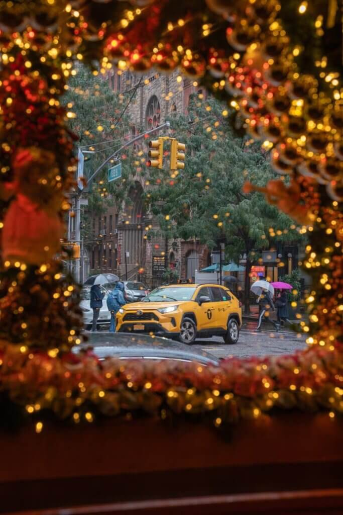 NYC yellow taxi seen through the christmas decor at Rolfs in NYC during the holidays