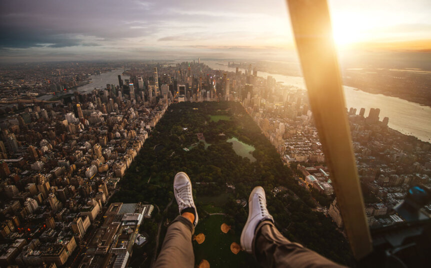 feet-dangling-out-of-an-open-door-helicopter-tour-in-NYC-over-Central-Park-in-Manhattan