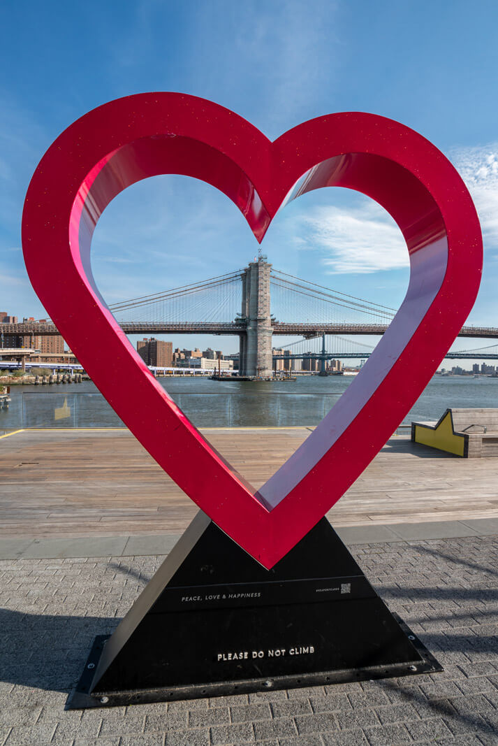 Peace Love and Happiness on Pier 17 in Seaport NYC the heart installation with the Brooklyn Bridge in the backdrop