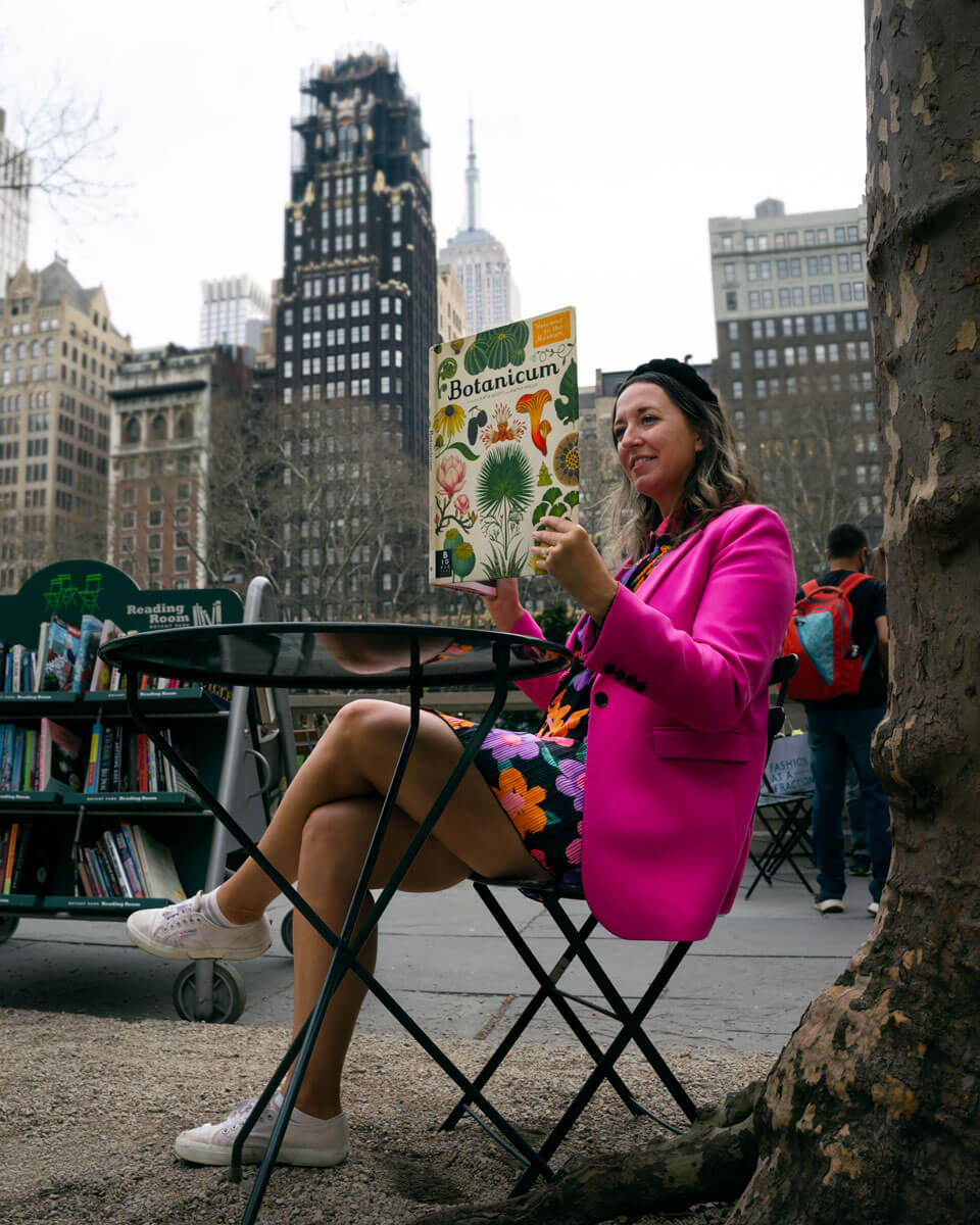 Megan-reading-a-book-from-the-library-in-Bryant-Park-with-a-view-of-the-Empire-State-Building-in-the-background-in-NYC